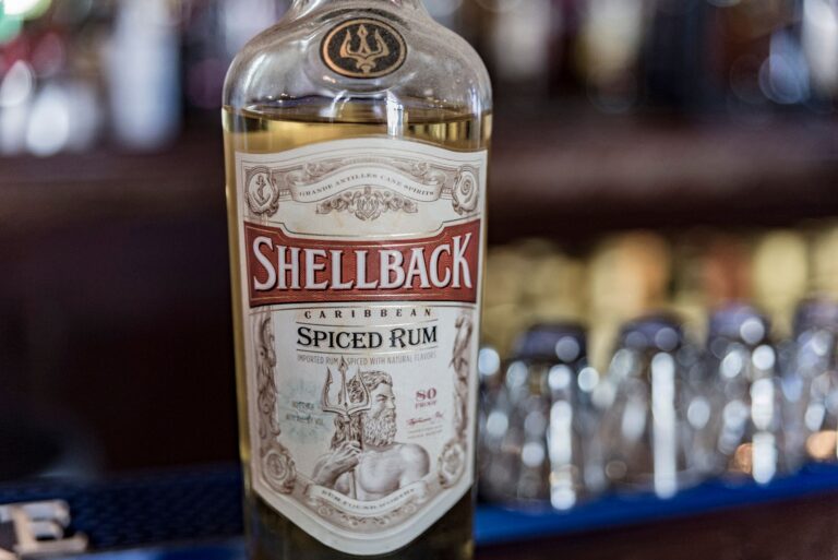 A detailed close-up of Shellback Caribbean Spiced Rum with a blurred bar background.
